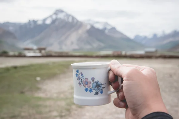 Hand holding coffee cup with Himalaya Mountain background, Rangd