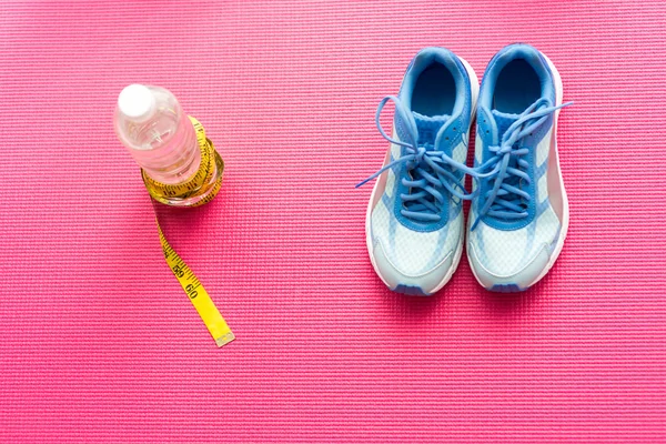 Sport shoes, bottle of water and centimeter on pink yoga mat,  S