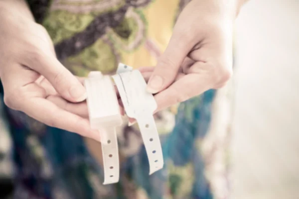 Blurry background mother showing new born name tags on her hands