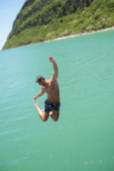 Blurry background man jumping to the sea.