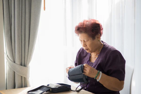 Asian senior woman checking blood pressure with window light