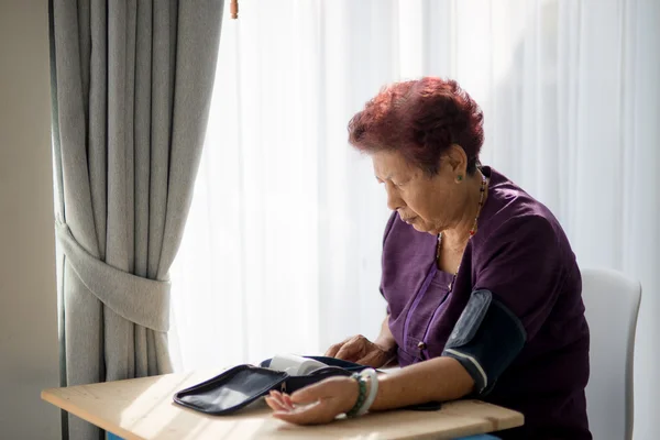 Asian senior woman checking blood pressure with window light
