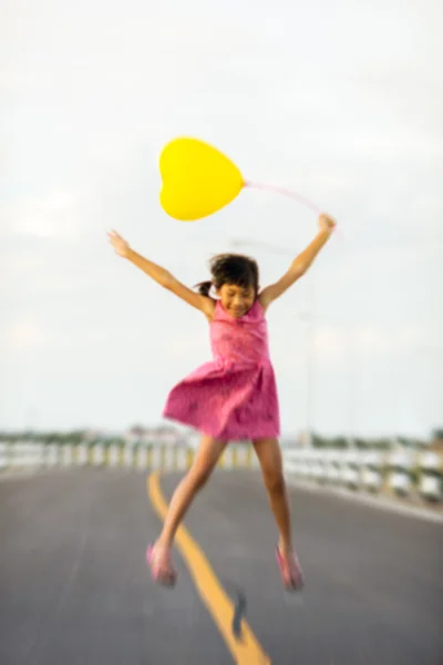Motion blurry background gild holding balloon jumping on the roa