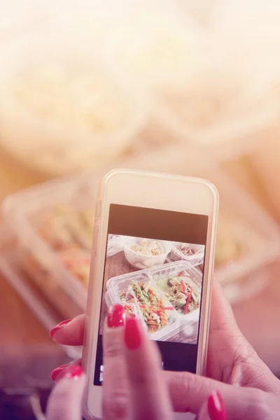 Woman hand with red nails taking photo of  food with smart phone