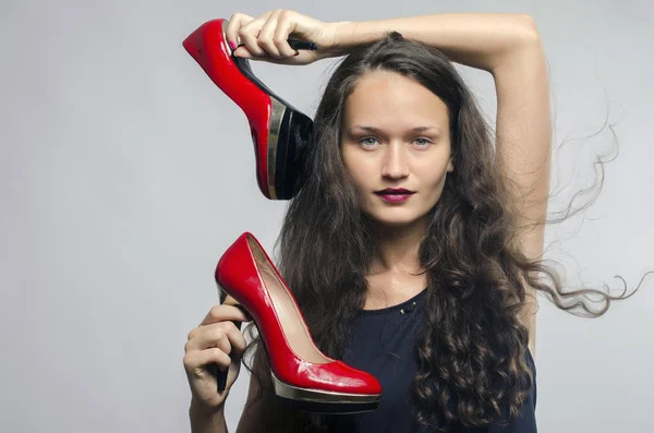 Woman in love with her high heel shoes. Beautiful girl holding her red sexy stiletto shoe. Lady shopping for shoes