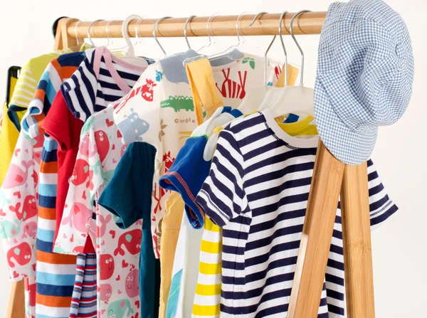 Dressing closet with clothes arranged on hangers.Colorful wardrobe of newborn,kids, toddlers, babies on a rack.Many t-shirts,pants, shirts,blouses, hat, onesie hanging