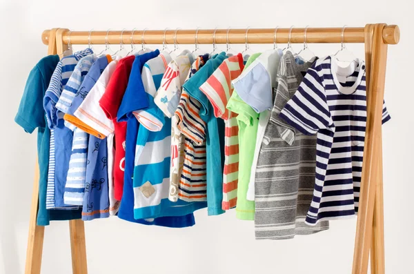 Dressing closet with clothes arranged on hangers.Colorful wardrobe of newborn,kids, toddlers, babies full of all clothes.Many t-shirts,pants, shirts,blouses, onesie hanging