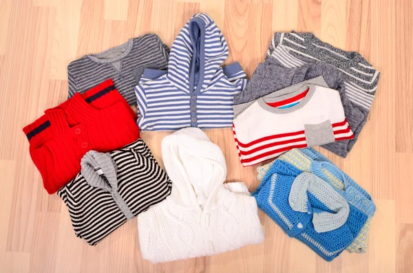 Baby clothes lying on the floor. Winter child sweaters arranged.