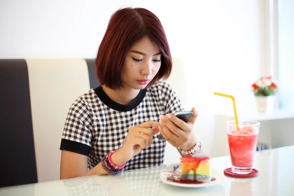 Portrait of young asian woman chatting mobile phone with a cake