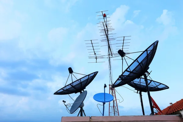 Satellite Dishes and TV antennas on the house roof with a beauti