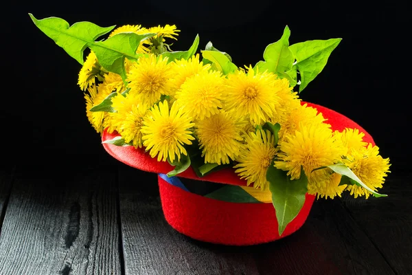 Festive bouquet of dandelions in a red hat