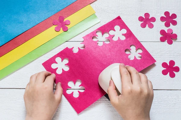 The child makes special hole punch flowers of paper