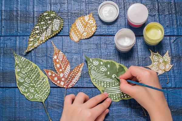 Girl paints patterns of dry autumn leaves