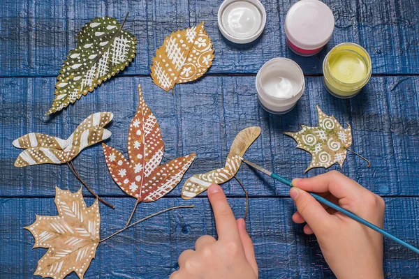 Girl paints patterns of dry autumn leaves