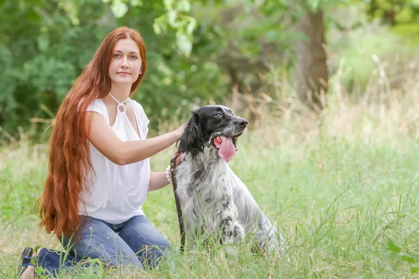 Outdoor portrait of young happy woman with dog on natural backgr