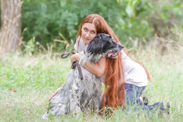 Outdoor portrait of young happy woman with dog on natural backgr