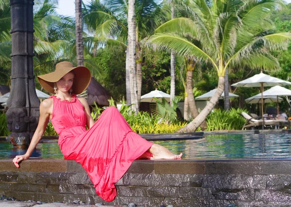 Young beautiful woman in hat relaxing near pool