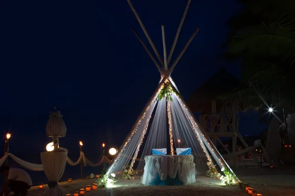 Wedding arch and set up with flowers on tropical beach at night