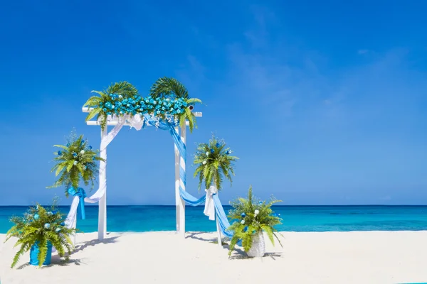 Wedding arch decorated with flowers on tropical sand beach, outd