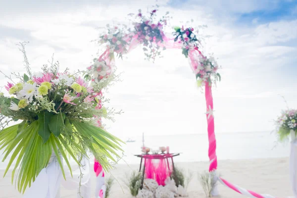 Wedding arch decorated with flowers on tropical sand beach, outd