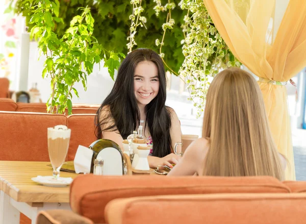 Two young happy women enjoying life in street cafe