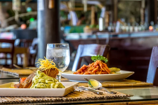 Grilled salmon steak served with pasta and vegetables in a small