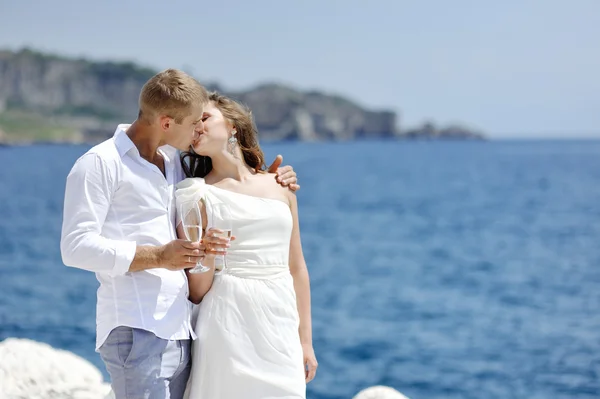 Just married bride and groom kissing near sea in wedding day