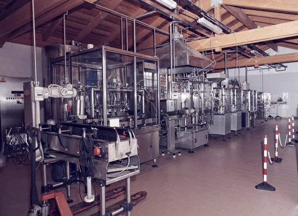 Wine bottling equipment line in a hangar, toned