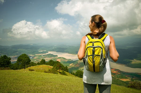 Portrait of happy traveler woman with backpack standing on top o