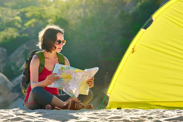 Young woman tourist nearby the tent looking into map