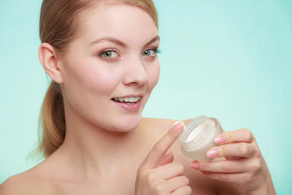 Woman applying cream on her skin face.