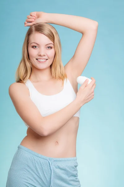 Girl applying stick deodorant in armpit.