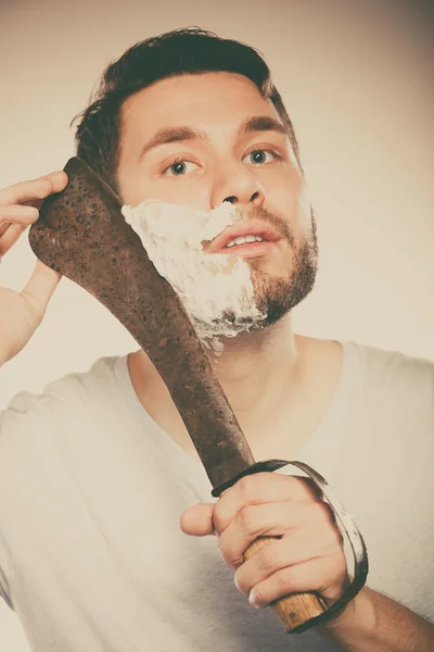 Young man shaving having fun with machete.