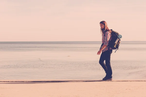 Man hiker with backpack tramping by seaside