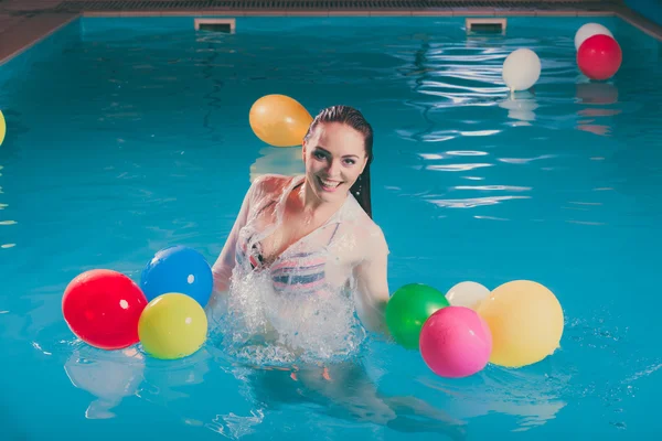 Happy woman in water having fun with balloons