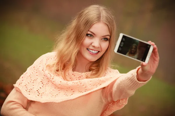Blonde young girl taking a selfie.