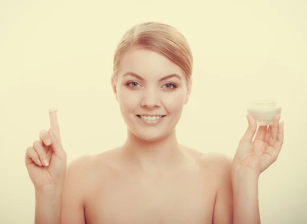 Woman applying cream on her skin face.