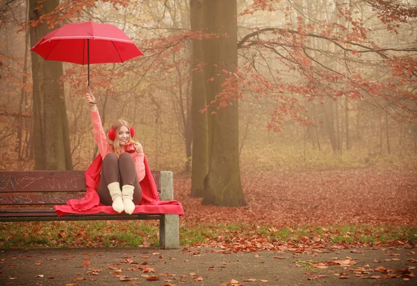 Girl sitting in park with umbrella