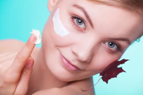 Skin care. Face of young woman girl with red maple leaf.