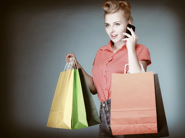 Pinup girl with shopping bags calling on the phone