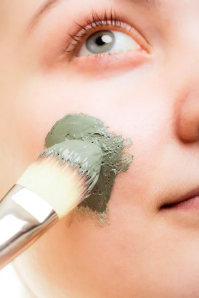 Woman applying clay mud mask