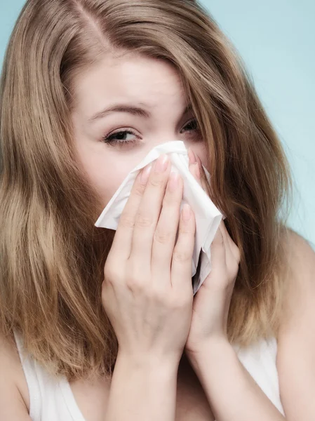 Sick girl sneezing in tissue.