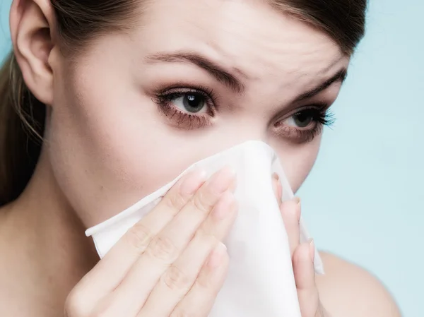 Sick woman sneezing in tissue.