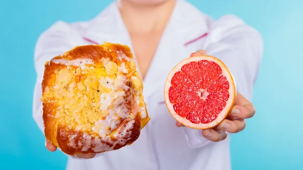 Nutritionist holding a cake and fruit