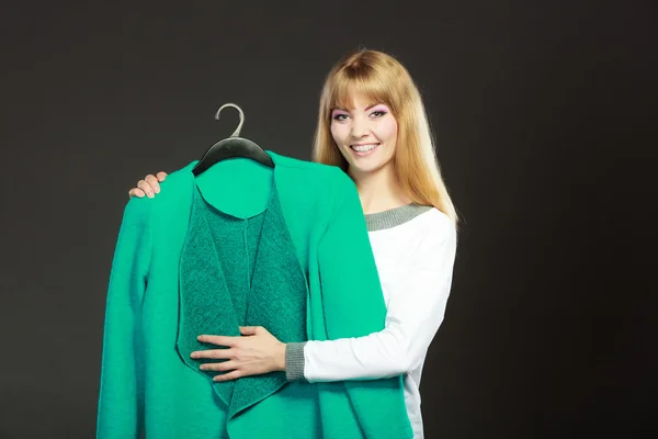 Fashionable woman holding green coat