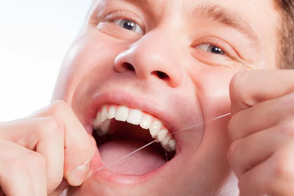 Man flossing his white teeth
