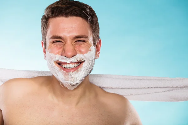 Happy young handsome man with shaving cream foam.