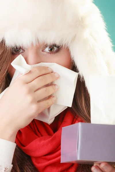 Woman in hat sneezing in tissue