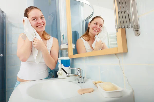 Woman washing her face with clean water in bathroom