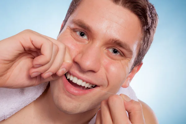 Young man cleaning her white teeth with dental floss